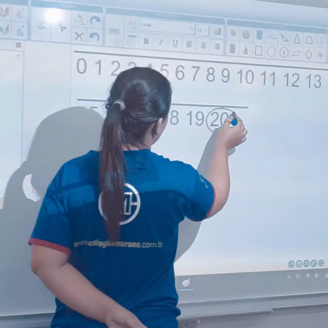 Educadora escrevendo números em lousa digital
