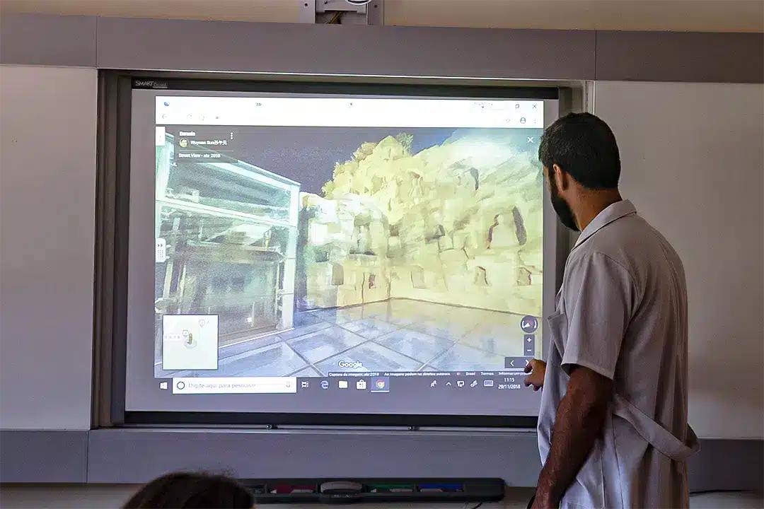 Lousa digital sendo manuseada pelo professor na sala