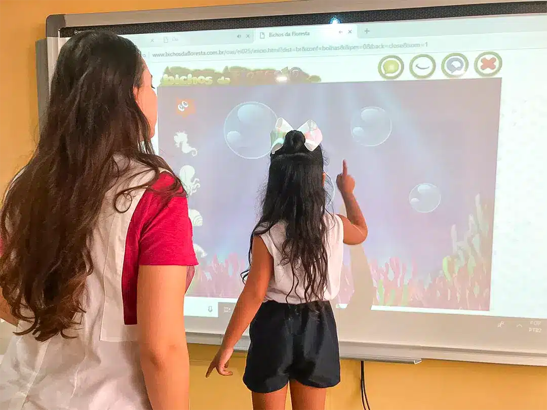 Jovens alunos em sala de aula utilizando a tela interativa